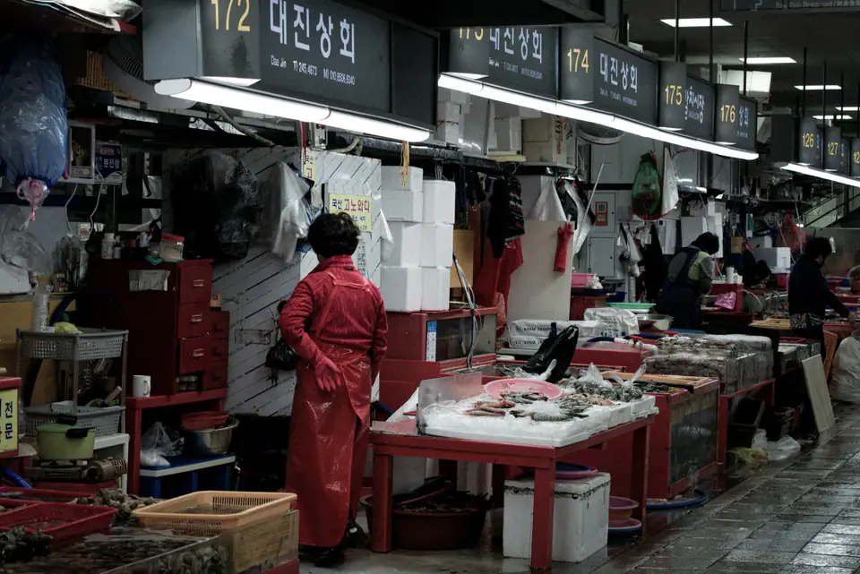 A fishmonger in red overalls on the market floor — Jagalchi Fish Market, Busan